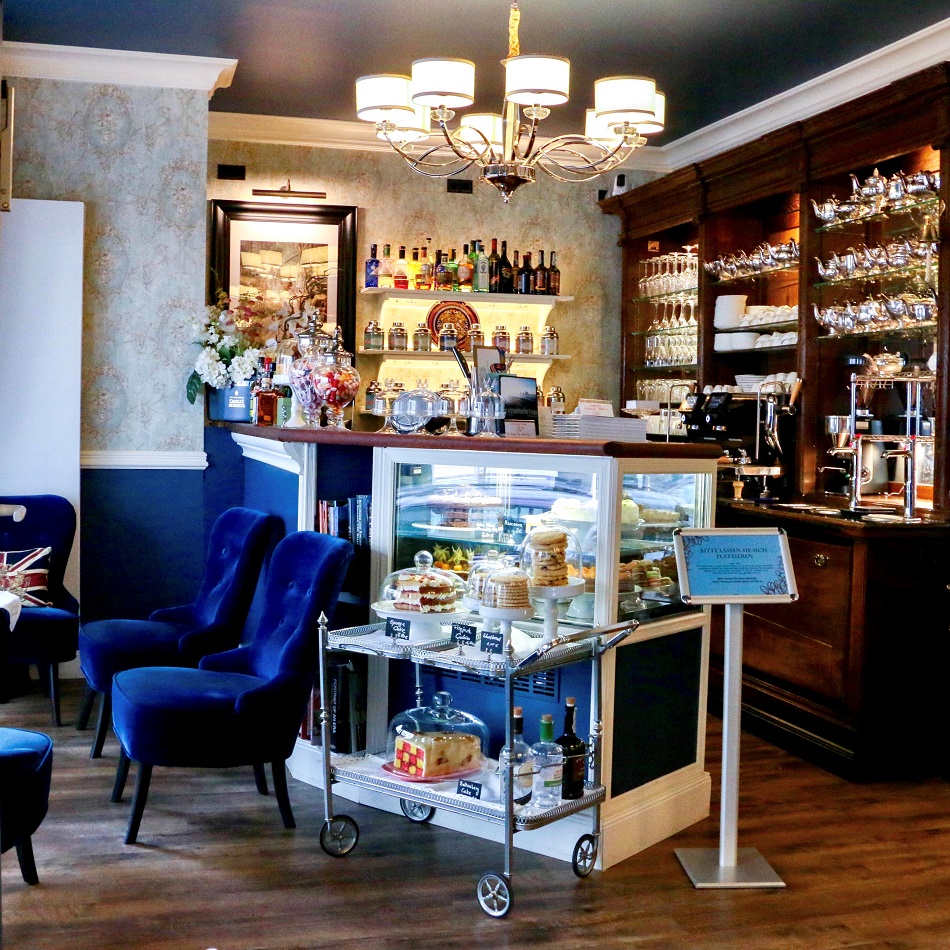 Lounge Sessel, ein Teewagen und die Bar des Eaton Place Café & Tearoom in Hamburg Ottensen mit vielen Teekannen in den Regalen
